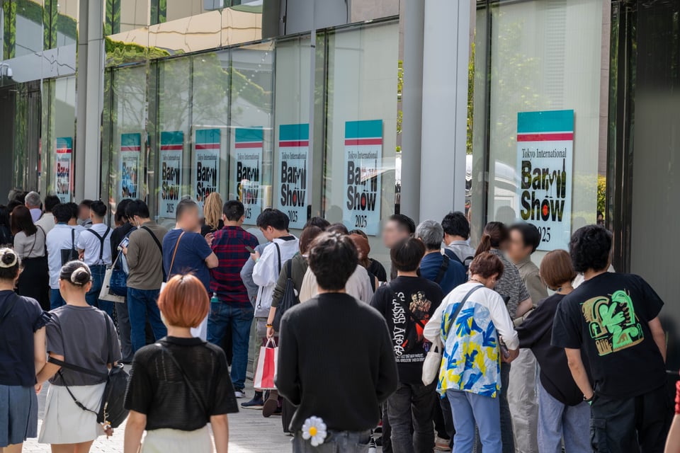 A long queue of international and domestic attendees waiting outside an event venue.